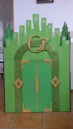 a green door with gold glitters and a monogrammed letter g on it