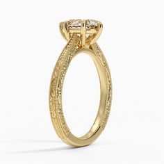 a yellow gold engagement ring with an intricate design and two round diamonds on the side