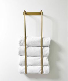 four folded white towels hanging on a gold towel rack