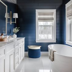 a blue and white bathroom with a tub in the corner, sink on the right