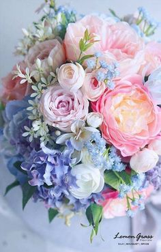 a bridal bouquet with pink, blue and white flowers in it's centerpiece