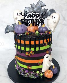 a halloween themed cake with ghost, pumpkins and decorations