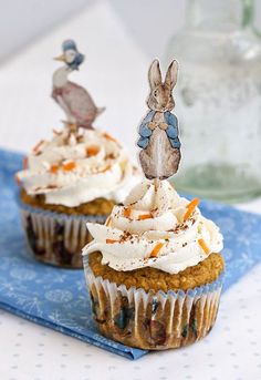 two cupcakes with frosting and decorations on them sitting on a blue napkin