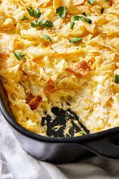 a casserole dish with cheese and herbs in it on a white table cloth