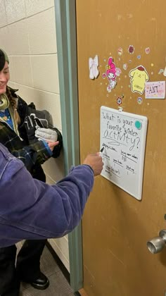 a woman is writing on the door to her dorm room