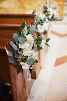 flowers and greenery line the pews of a church