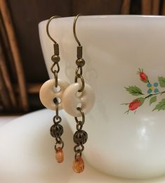 This cute pair of earrings contain reclaimed/repurposed vintage cream colored ceramic buttons and small dangling orange glass bead.  Brass toned findings.  Earring length can be seen in photos. Please review photos carefully...photos show detail and condition.  Ask questions prior to purchasing. Perfect for any occasion!  Would make a nice birthday gift or fun addition to your own wardrobe.  Earring hooks are sterling silver. Vintage Handmade Beige Jewelry, Vintage Everyday Earrings, Vintage Orange Czech Glass Earrings, Vintage Orange Earrings With Czech Glass, Vintage Handmade Cream Jewelry, Vintage Orange Dangle Earrings, Vintage Orange Nickel-free Earrings, Button Creations, Ceramic Buttons