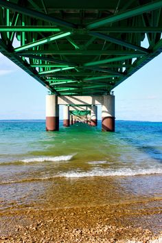 the underside of a green bridge over water