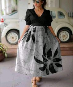 a woman standing in front of a car wearing a black and white dress with flowers on it