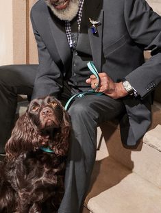 a man in a suit and tie sitting next to a dog