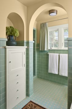 a green tiled bathroom with an arched doorway