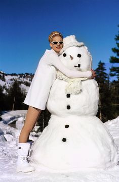 a woman is hugging a snowman in the snow