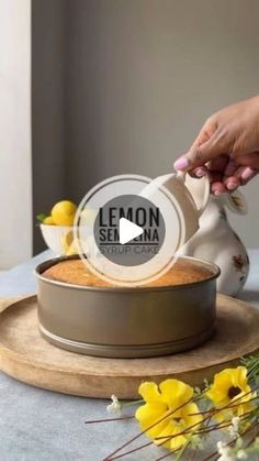 a person is pouring lemon into a cake in a pan on a table with yellow flowers