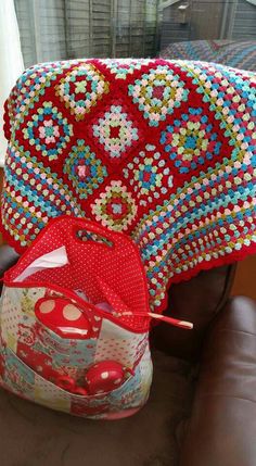 a crocheted red blanket sitting on top of a brown chair