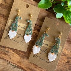 two christmas themed earrings on top of a wooden table