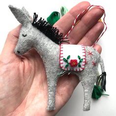 a hand holding a small gray horse ornament