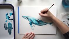 someone is painting a blue whale with watercolors