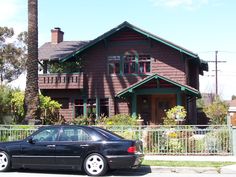 a black car parked in front of a brown house