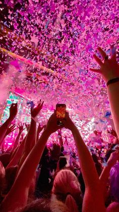 a group of people in a room with confetti on the ceiling and one person holding up a cell phone