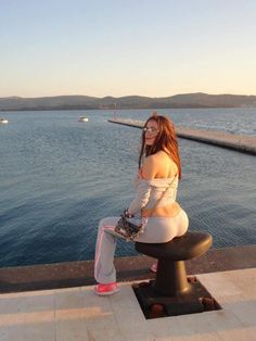 a woman sitting on top of a bench next to the ocean