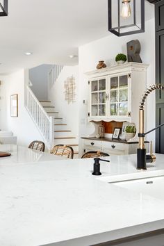 a kitchen with white counter tops and black cabinets in front of a staircase leading up to the second floor