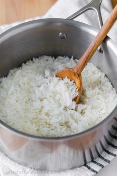 rice is being cooked in a pot with a wooden spoon on a towel next to it