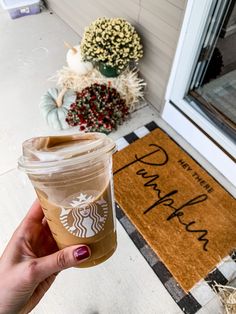 a person holding up a cup of coffee in front of a door with the words happy thanksgiving written on it