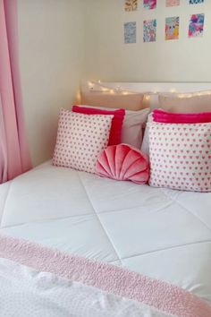 a bed with pink and white pillows on top of it