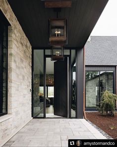 the front entrance to a house with black doors and brick walkway leading up to it