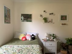 a bedroom with two stuffed animals on the bed and plants in baskets around the room