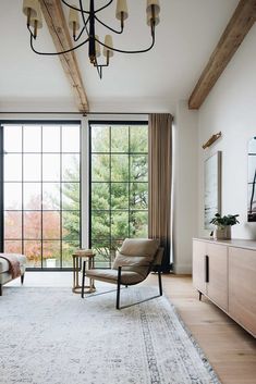 a living room with large windows and a chair in front of the window that is open