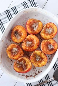 a white bowl filled with sliced peaches on top of a table next to a spoon