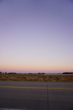 an empty road with no cars on it at dusk or dawn, in the middle of nowhere