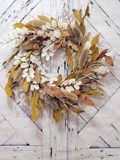 a wreath made out of dried flowers and leaves on a white wooden background with water drops