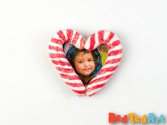 a red and white striped heart shaped brooch with a child's face in it