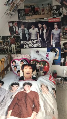 a bed with many pictures on the wall and one has a hat on his head