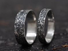 two silver rings with etched designs on them