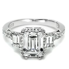 an emerald cut diamond ring with three baguets on the shoulders and side stones