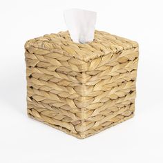 a tissue dispenser made out of wicker with a white napkin on top