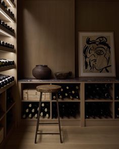 a wine cellar filled with lots of bottles next to a wooden table and stools