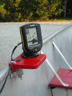 an electronic device sitting on top of a red bench next to a forest in the background