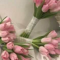 a bouquet of pink tulips laying on top of a white cloth covered bed