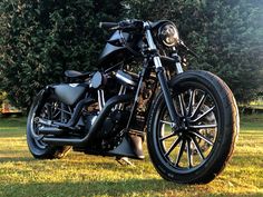 a black motorcycle parked on top of a lush green field next to some tall trees