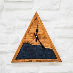 a clock made out of wood on the side of a white brick wall with blue fabric