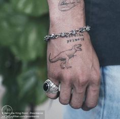 a man with a tattoo on his arm wearing a silver bracelet and a dinosaur ring