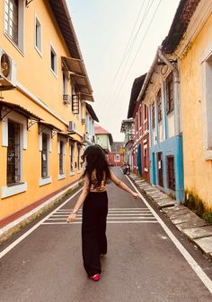 a woman is walking down the street in front of some buildings and holding her arms out