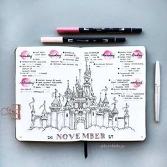 an open notebook with disney castle drawings and markers on it, next to two pens