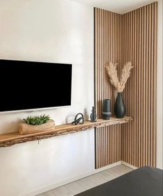 a flat screen tv sitting on top of a wooden shelf next to a wall mounted television