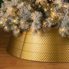 a christmas tree in a gold tinsel pot with white lights on the top and bottom