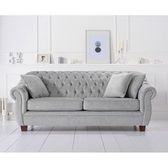 a grey couch sitting on top of a white floor next to a framed photo and pictures